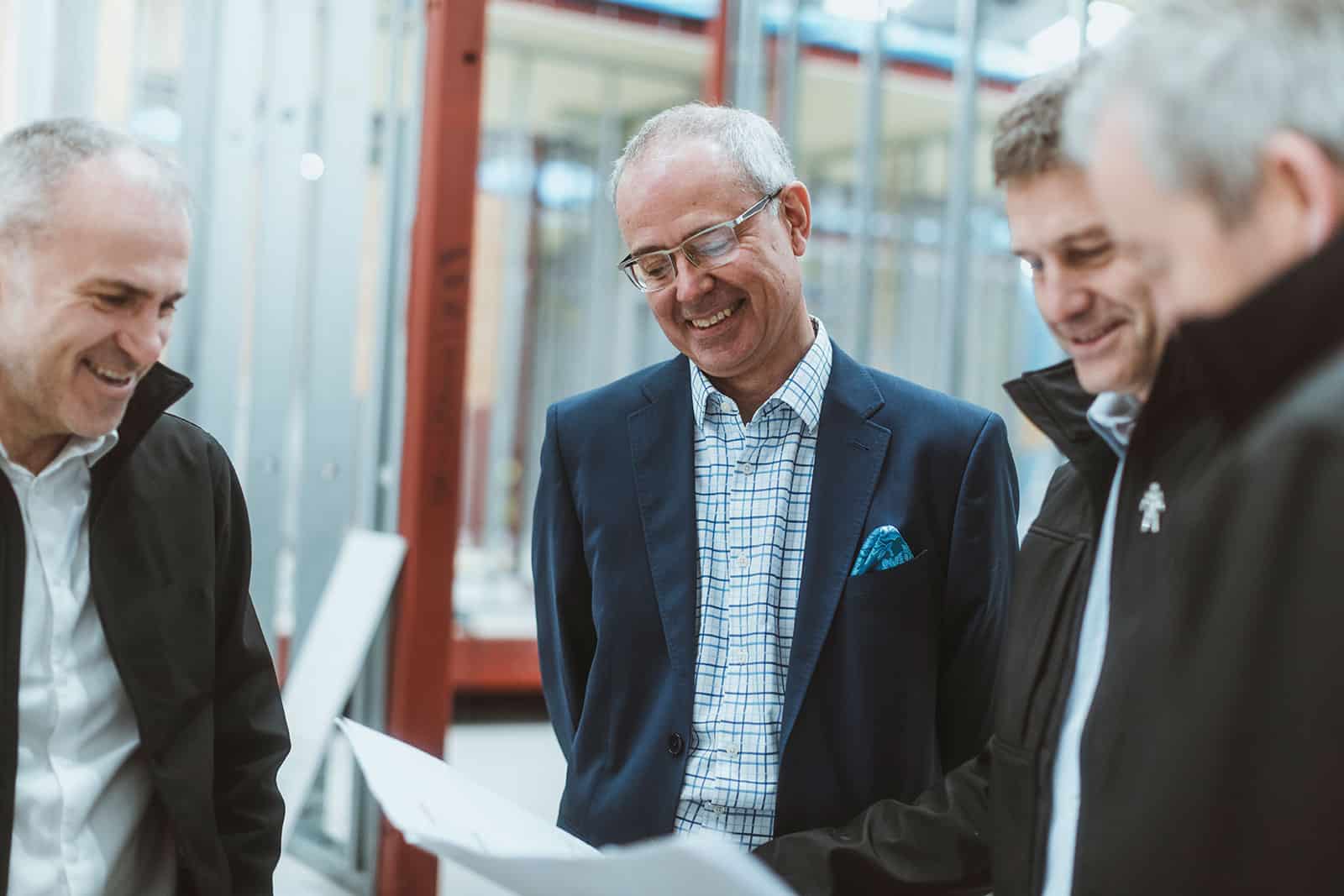 A group of our team assembled around an offsite construction plan, smiling and discussing.