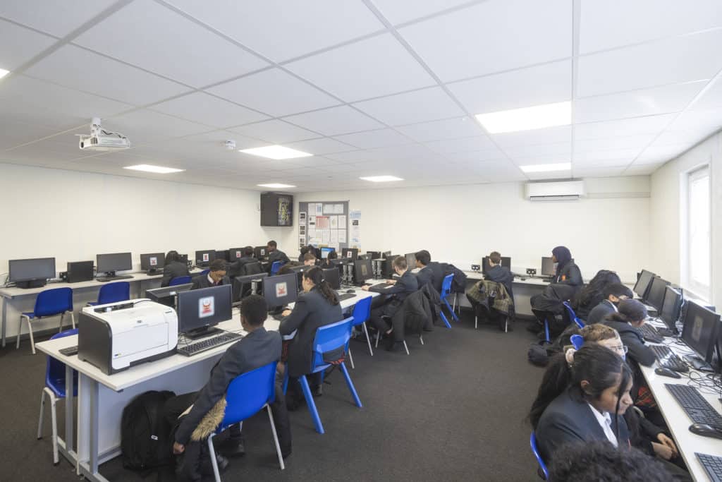 inside a temporary classroom built for a computer class. Children sat around desks working on computers.