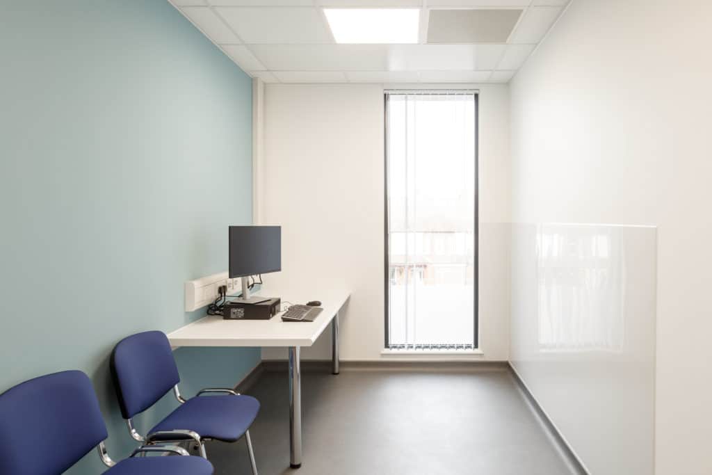 2 waiting chairs, a computer in a small consulting room. Part of a modular medical building. 