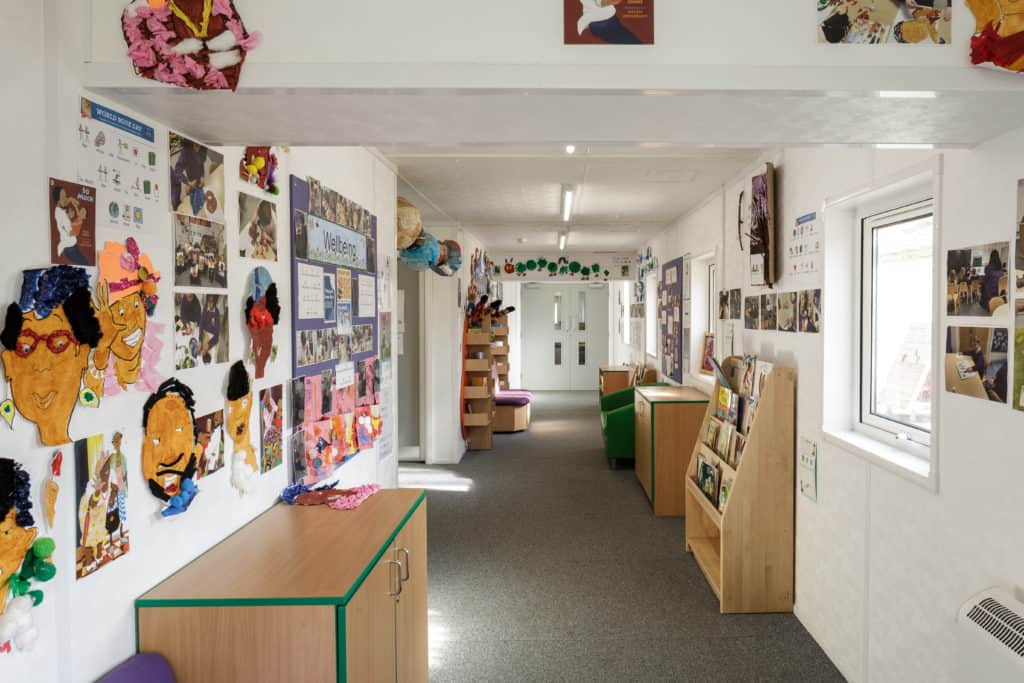 Inside view of a modular classroom. Cupboards and small library space, with hand drawn pictures on the walls.