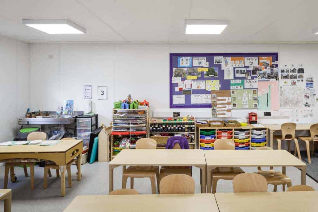 Inside view of a portable classroom, desks, small chairs and typical items that are in usual primary school facilities.