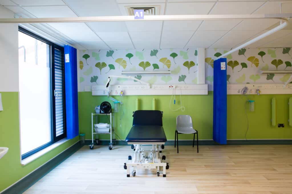 Hospital room with a hospital bed in the centre alongside medical equipment. Part of a modular healthcare building