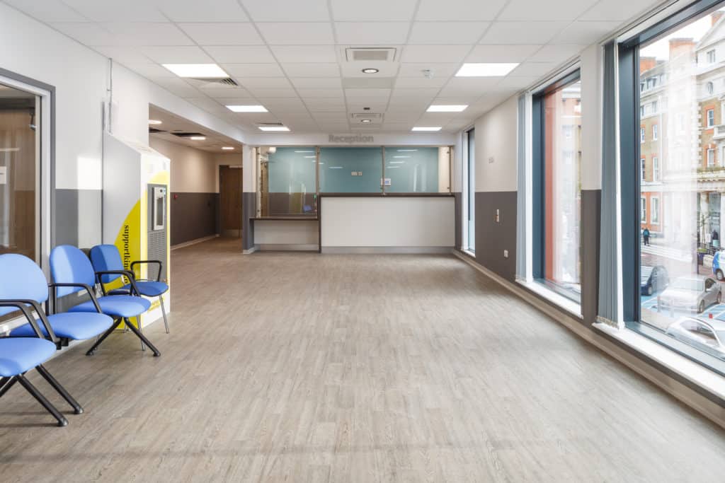 Reception area in modular hospital. High levels of natural light, desk area and waiting area chairs.
