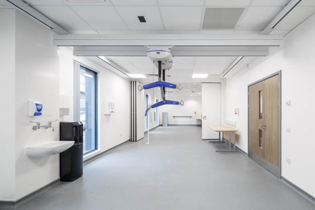 Inside modular hospital building. Medical equipment, white walls, open space, windows. 