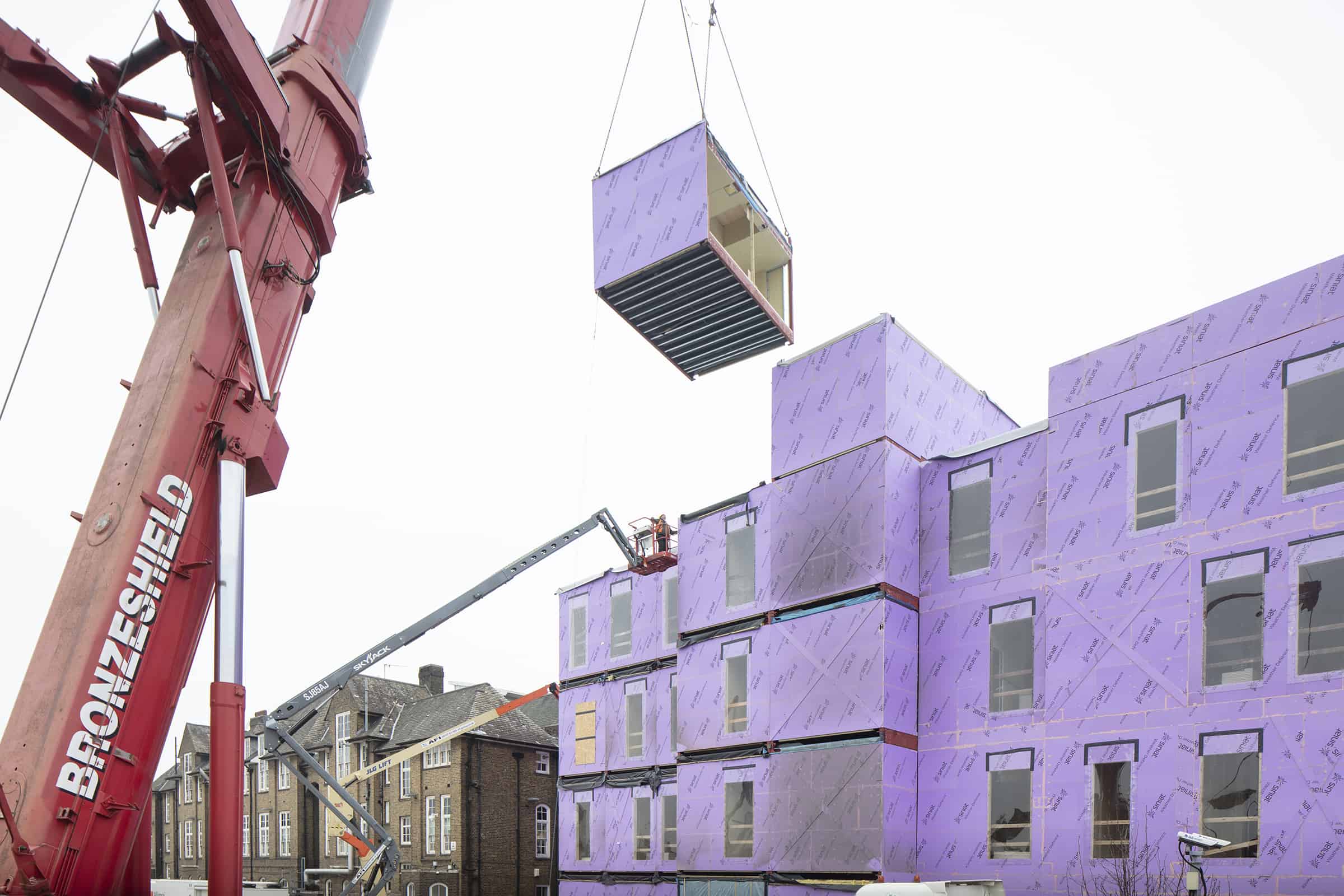 A crane lifting a modular unit onto a building that has been prefabricated off-site. 