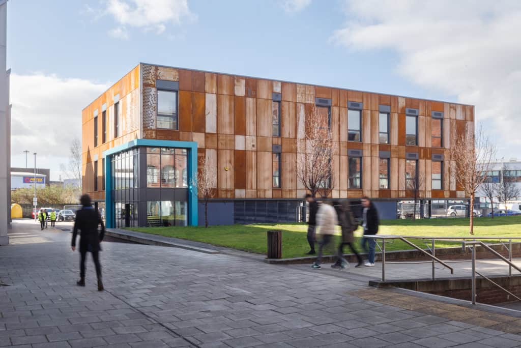 Full outside view of modular school building built for Leeds City College, with students walking around campus.