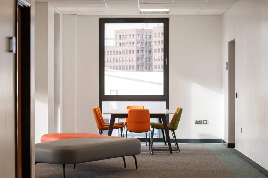 A learning space inside a modular school. Table and chairs in front of large window. 