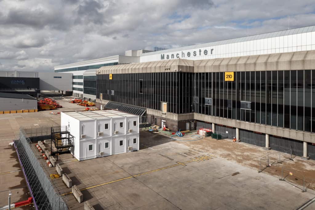 Long view of the outside of Manchester Airport, with temporary modular buildings displayed outside. 