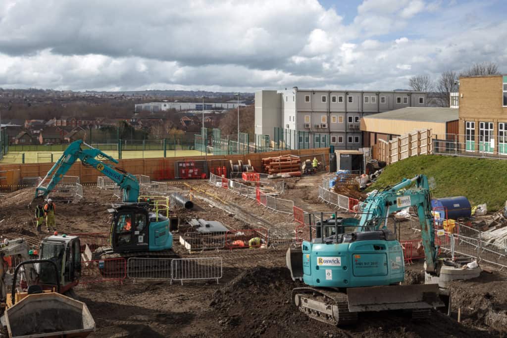 Construction happening onsite. Temporary classroom facilities in the back of the image.