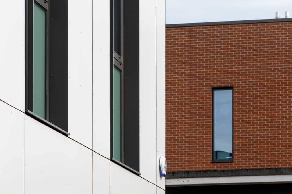 Close shot of the outside of this modular education building, white panels and windows with grey frames.