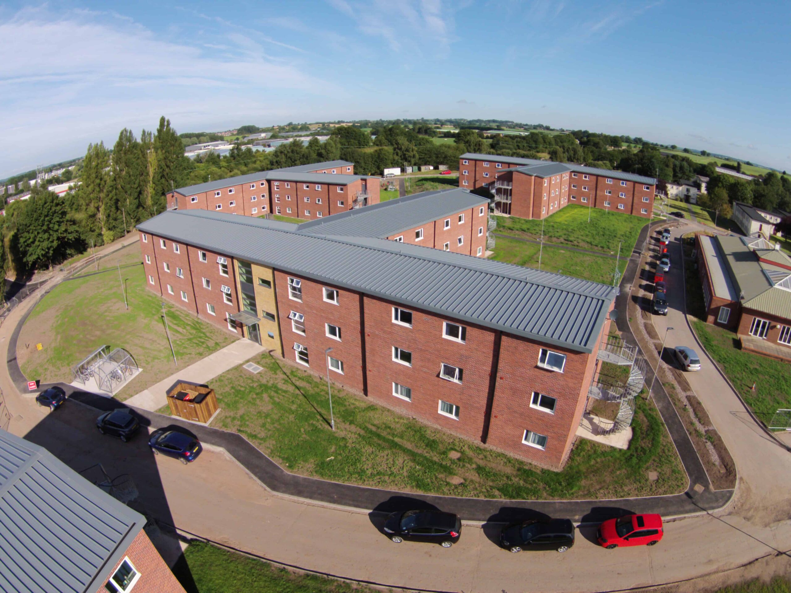 Accomodation Complex for residents of the Ministry of Defence. Large building, with cars parked on the street. 