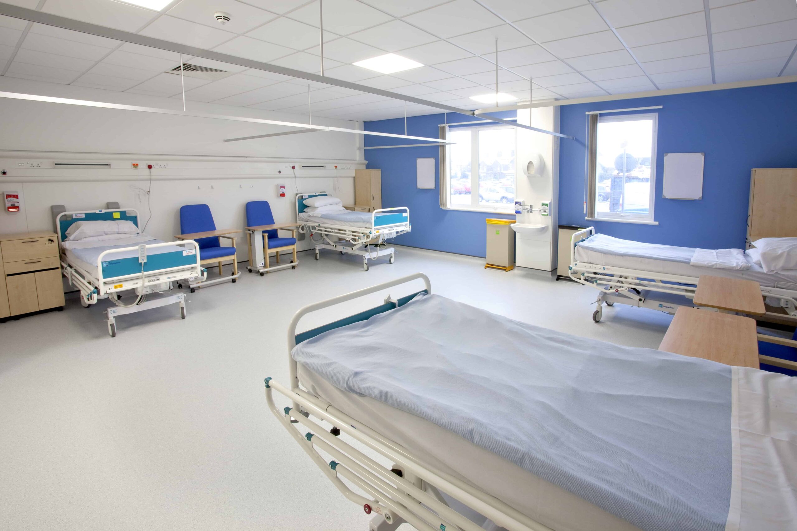 Hospital beds with chairs, inside a modular healthcare room. 